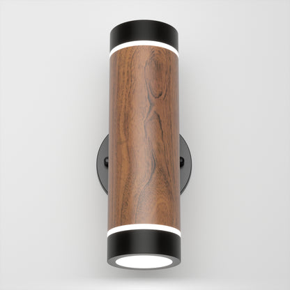 The Artika C7 indoor-outdoor LED wall light 3 CCT features a cylindrical wooden body, black metal ends, and circular white LED lights on the top and bottom, shown mounted on a white wall.