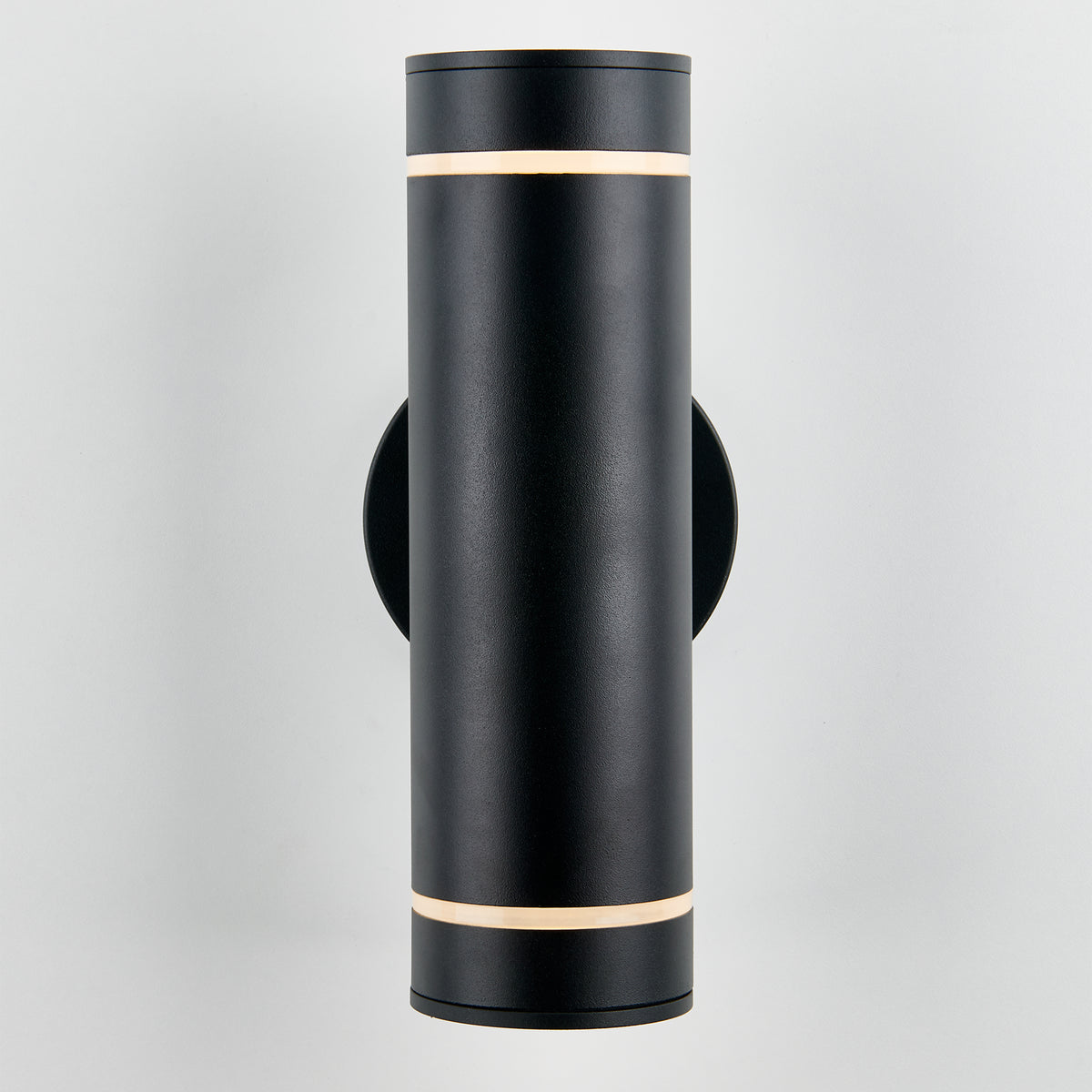 The Artika C7 indoor-outdoor wall light is a modern cylindrical black fixture with slim illuminated bands at the top and bottom, mounted on a light-colored wall—perfect for versatile lighting needs.