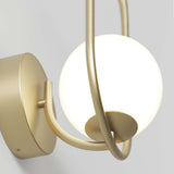 A close-up of a modern wall sconce featuring a round frosted glass globe held by curved, brushed gold metal supports against a light gray background.
