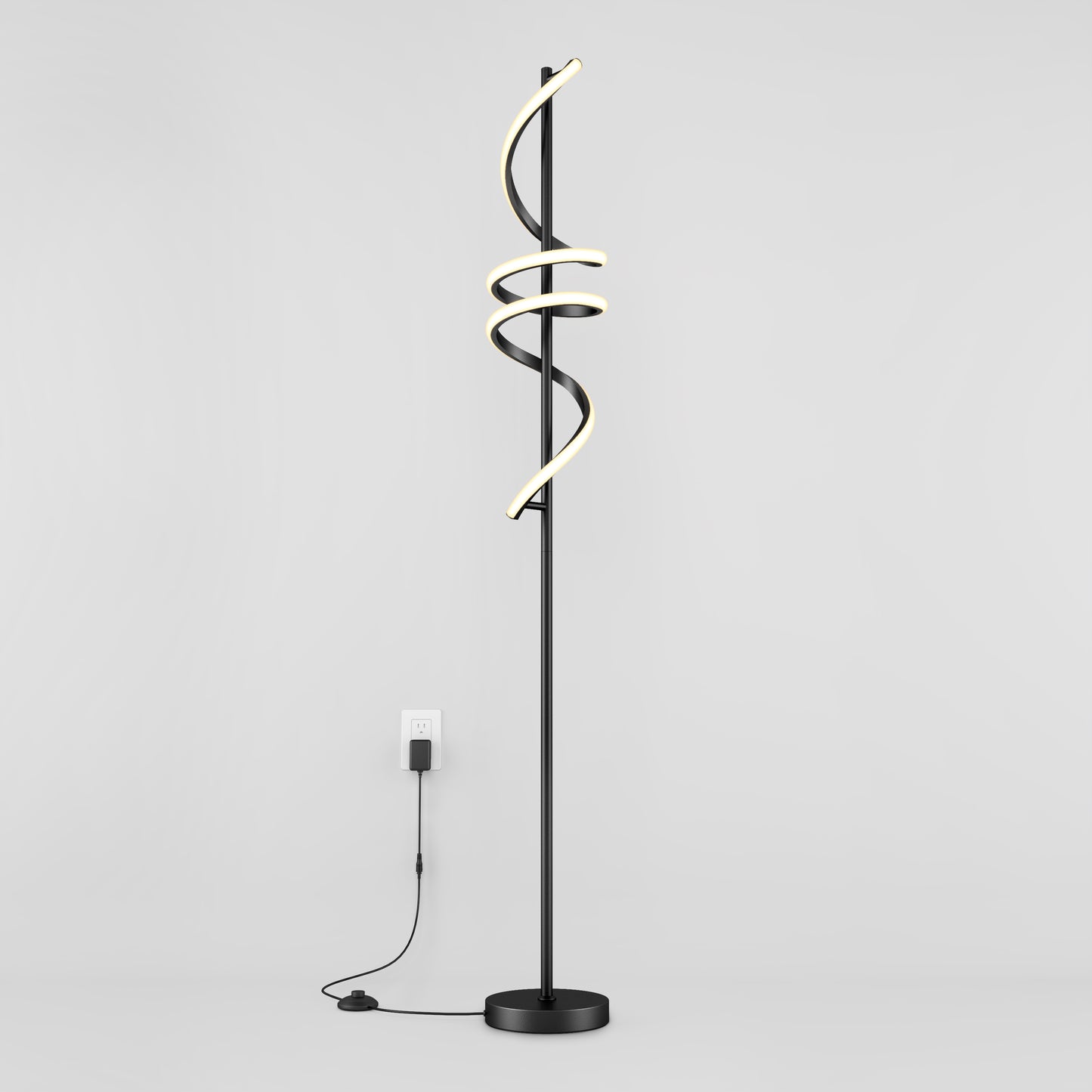 The Artika Coda modern LED floor lamp 5CCT features a black stand with three spiral LED light tubes, dimmable for customizable ambiance, standing against a white wall and plugged into a wall outlet.