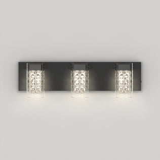 The Artika Crystal Cube LED bathroom vanity light features three glass and metal cylindrical lamps, each emitting a bright, soft white glow against a light gray wall.