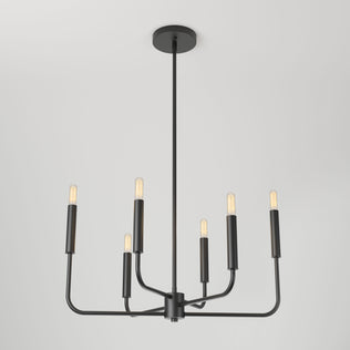 The Artika Manchester 6-light pendant is a modern black chandelier featuring six exposed bulbs in a circular design, suspended from the ceiling by a long central rod against a plain white background.
