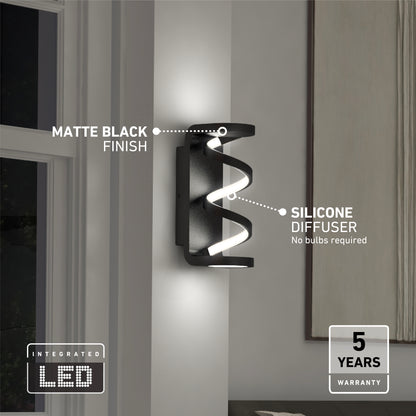 The Artika Swirl indoor-outdoor LED wall light features a matte black finish, silicone diffuser, integrated LED (no bulbs needed), and comes with a 5-year warranty—ideal for indoor mounting near windows.