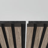Close-up of vertical wooden panels with dark gaps between them, arranged against a plain light background, creating a symmetrical, modern, and geometric pattern.