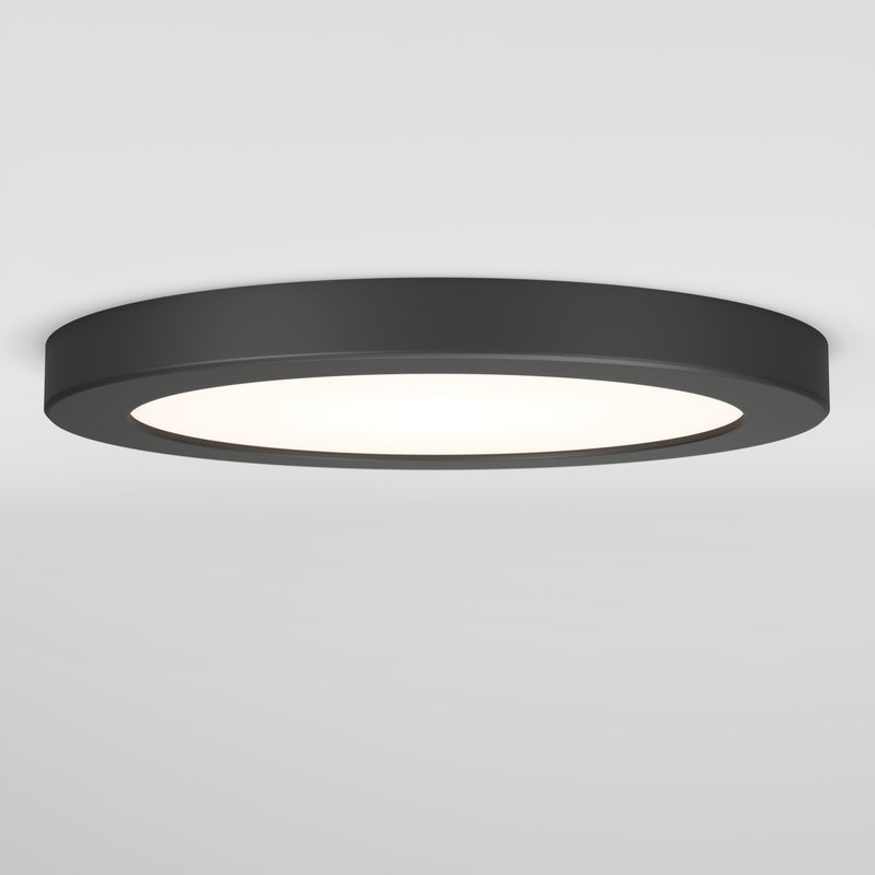 The Artika Europa Disk 7 in. LED modern flush mount light features a flat, round black design and offers 3 CCT options, emitting bright white light against a plain white ceiling and wall.