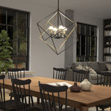 A modern dining room with a wooden table, black chairs, decorative vases, and a geometric pendant light fixture. Large windows show greenery outside, and there is a gray sofa and bookshelf in the background.