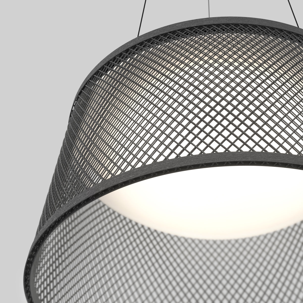 Close-up of a modern pendant light with a black metal mesh shade and a glowing white inner diffuser, suspended by two thin wires against a plain gray background.