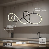 Modern LED pendant light with a matte black finish hangs above a minimalist kitchen island. Labels highlight its energy efficiency, integrated LED (no bulbs needed), and a 5-year warranty.