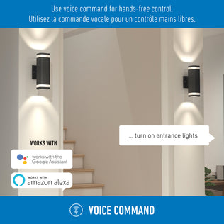 A modern hallway with lit Stark LED lights by Artika and stairs; text above says, “Use voice command for hands-free control.” Google Assistant and Amazon Alexa logos show wi-fi compatibility for entrance lighting.
