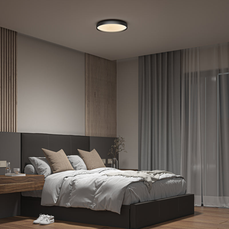 A modern bedroom features a large bed with neutral bedding, two pillows, a wooden nightstand with a vase, floor-to-ceiling curtains, and the Artika Celestia 15 in. modern LED flush mount light with remote brightening the space.