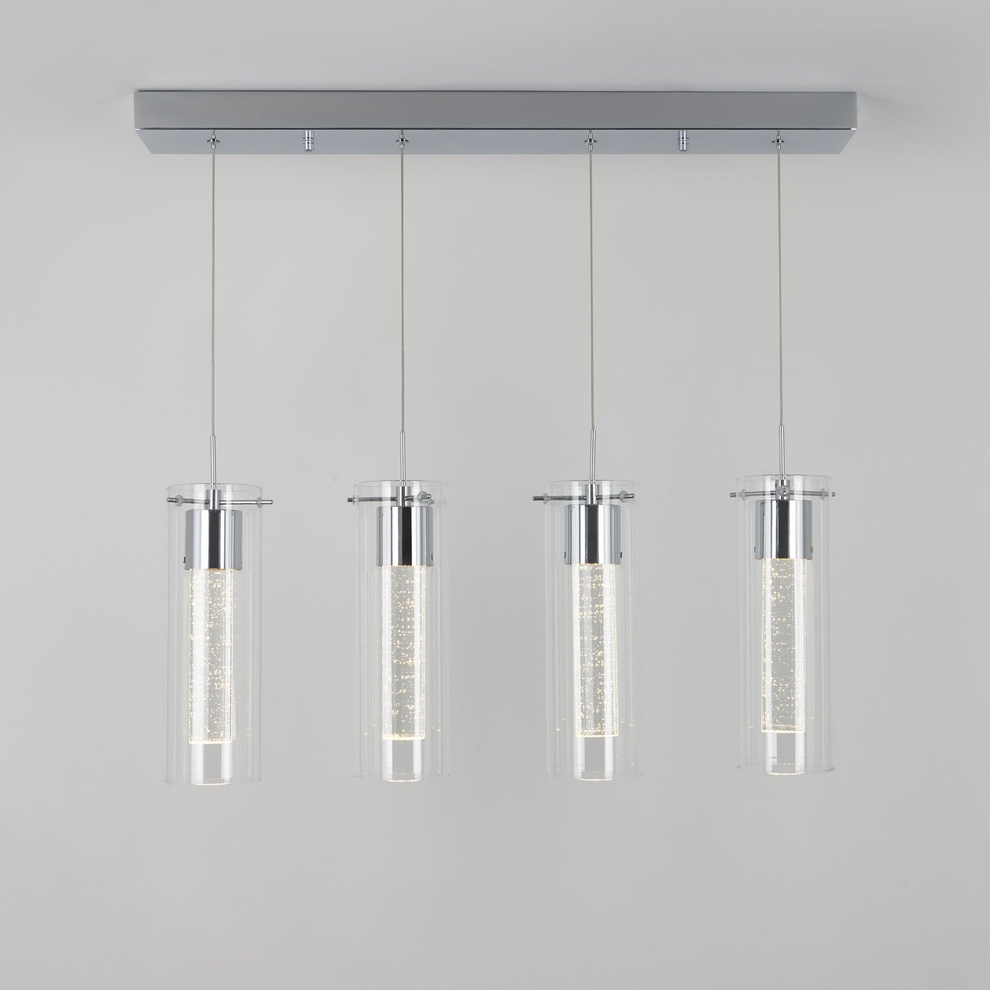 The Artika Essence 4-light LED pendant features four cylindrical glass shades suspended by thin wires with chrome accents, shown against a plain light gray background.