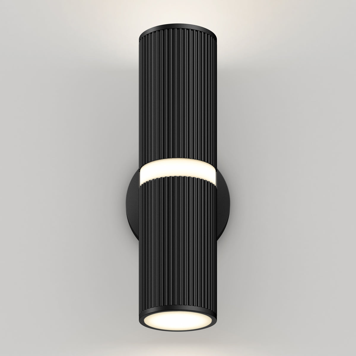 A modern black cylindrical wall sconce with vertical grooves emits light from the top and bottom, mounted on a plain white wall.