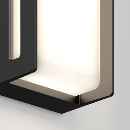 Close-up of the Artika Ryker smart RGB indoor-outdoor wall light, showcasing its black and metallic geometric frame with customizable soft illumination against a light gray background.