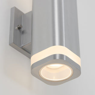 A close-up of the Artika Mettle LED indoor-outdoor wall light features a modern stainless steel design with a brushed finish and glowing LED ring, mounted on a white wall.