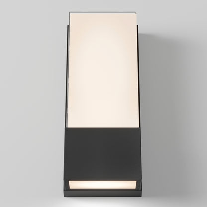 The Artika Dixon indoor-outdoor LED wall light features a rectangular design with a frosted top panel, matte black base, and emits a soft warm glow—perfectly mounted on a light gray wall.