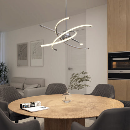 A modern dining room features a round wooden table, four gray upholstered chairs, a Silvio LED pendant light by Artika, a vase with a branch, and a magazine, with light wood cabinets and abstract wall art in the background.