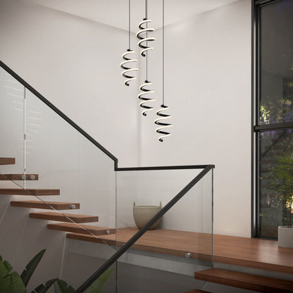 A modern staircase with wooden steps and glass railings features the Artika Chorus 4 light LED pendant 5 CCT. Large windows bring in natural light, and a potted plant decorates the corner.
