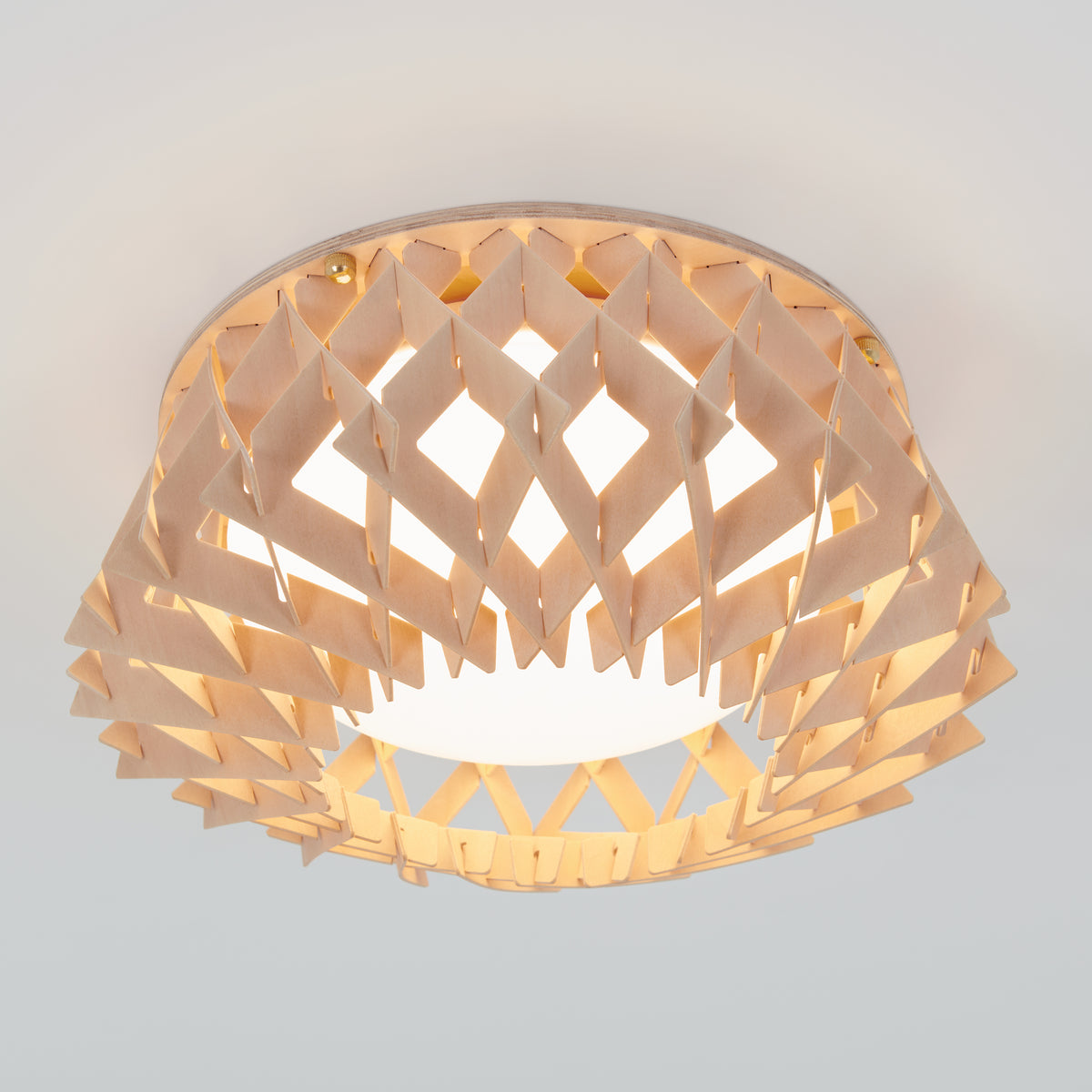A modern ceiling light fixture with a geometric, lattice-patterned wooden shade, allowing light to diffuse softly through the angled wooden slats. The light emits a warm, inviting glow.