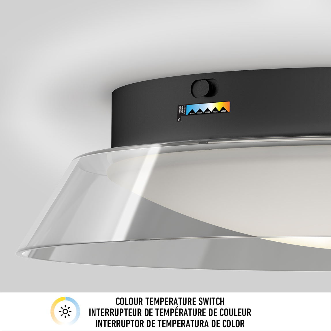 Close-up of a black ceiling light fixture with a transparent shade, featuring a color temperature switch and indicator with five color settings. Text below describes the switch in English, French, and Spanish.