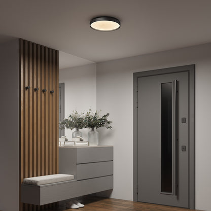 A modern entryway with a gray door, wooden floor, cushioned bench, vertical wooden slats with wall hooks, floating cabinet, decorative vases with greenery, and the Artika Celestia 15 in. modern LED flush mount light with remote.