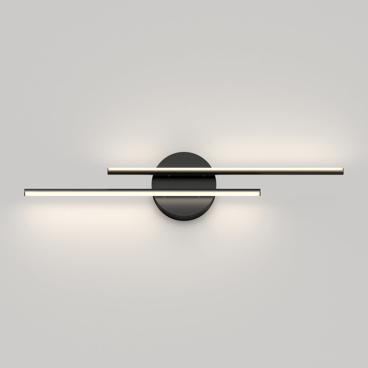 A modern wall light fixture with two horizontal, parallel light bars mounted on a round black base, emitting soft white light against a plain gray wall.