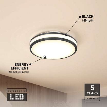 The Artika Hemisphere 15 in. LED flush mount light 5 CCT, in a sleek black finish, is installed on a beige ceiling. It features energy efficiency, adjustable color temperatures, integrated LED technology, and a 5-year warranty—ideal for bathrooms.
