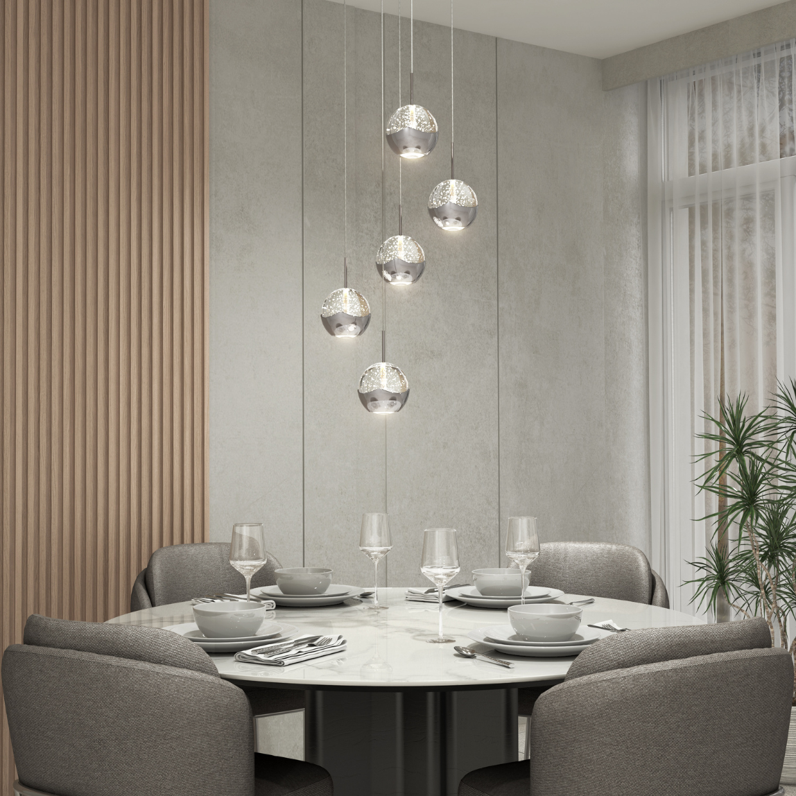 A modern dining room with a round marble table set for four, gray upholstered chairs, hanging glass pendant lights, wooden wall paneling, large windows with sheer curtains, and a potted plant in the corner.